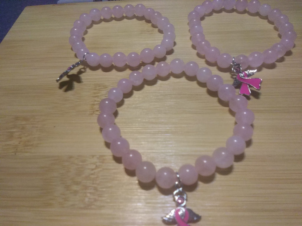 Handmade rose quartz healing stone bracelets featuring silver angel charms with breast cancer awareness pink ribbons, displayed as a set of three.