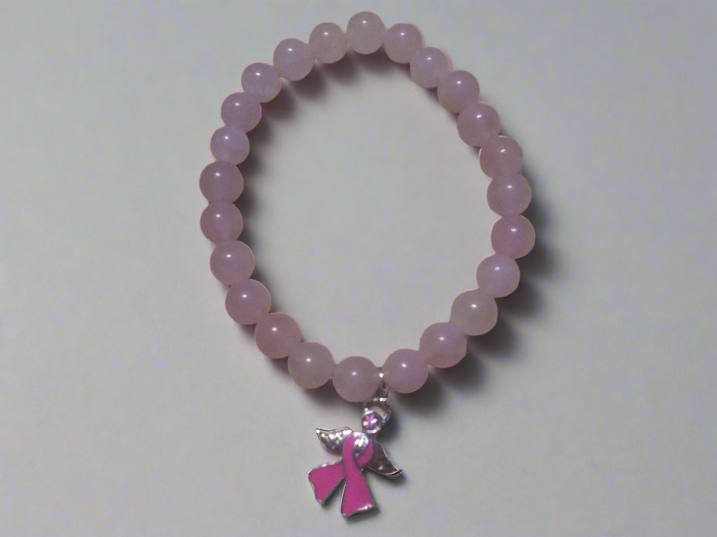 Pink beaded bracelet with a pink ribbon charm on a wooden surface