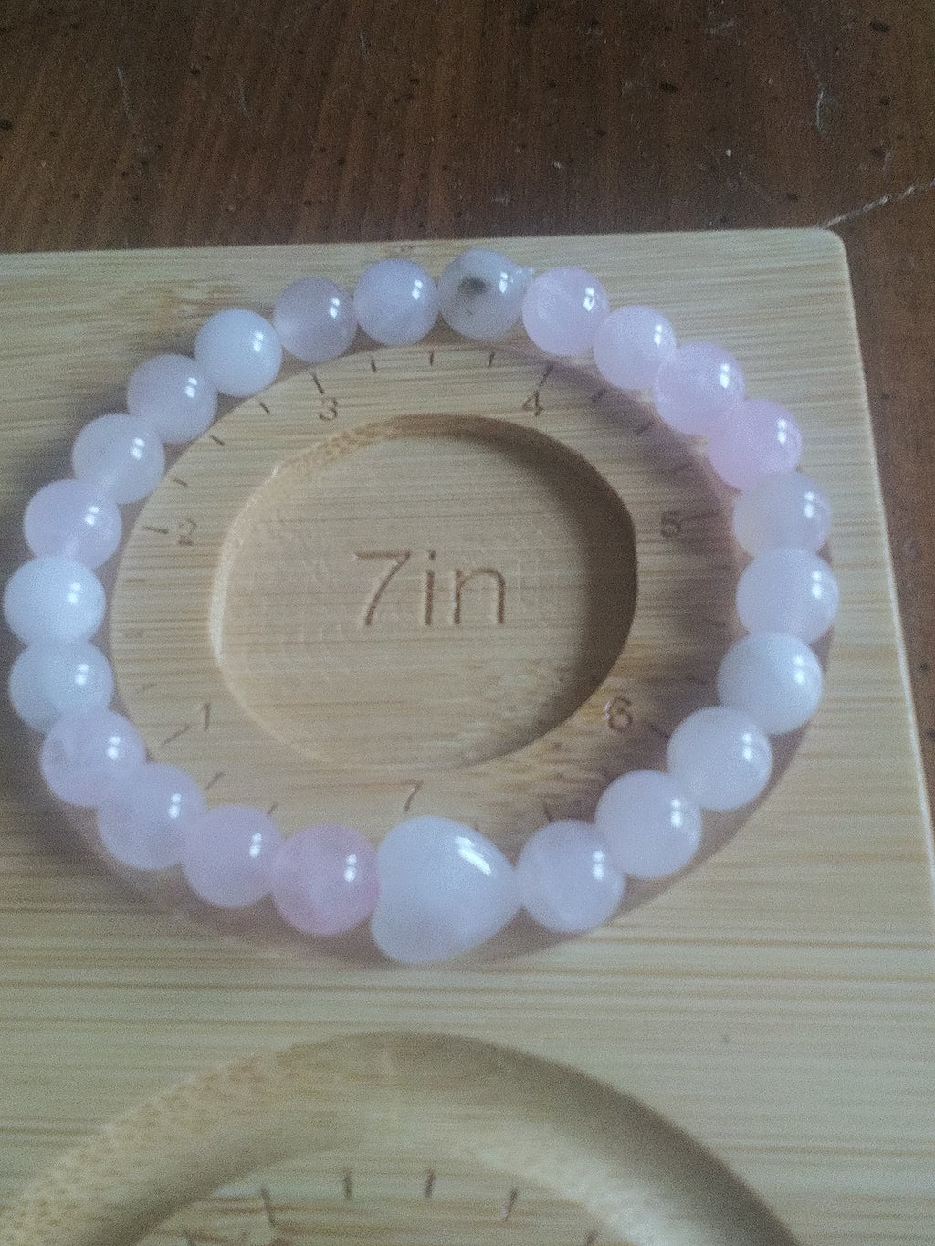 Pink beaded bracelet on a wooden stand with a heart focal bead
