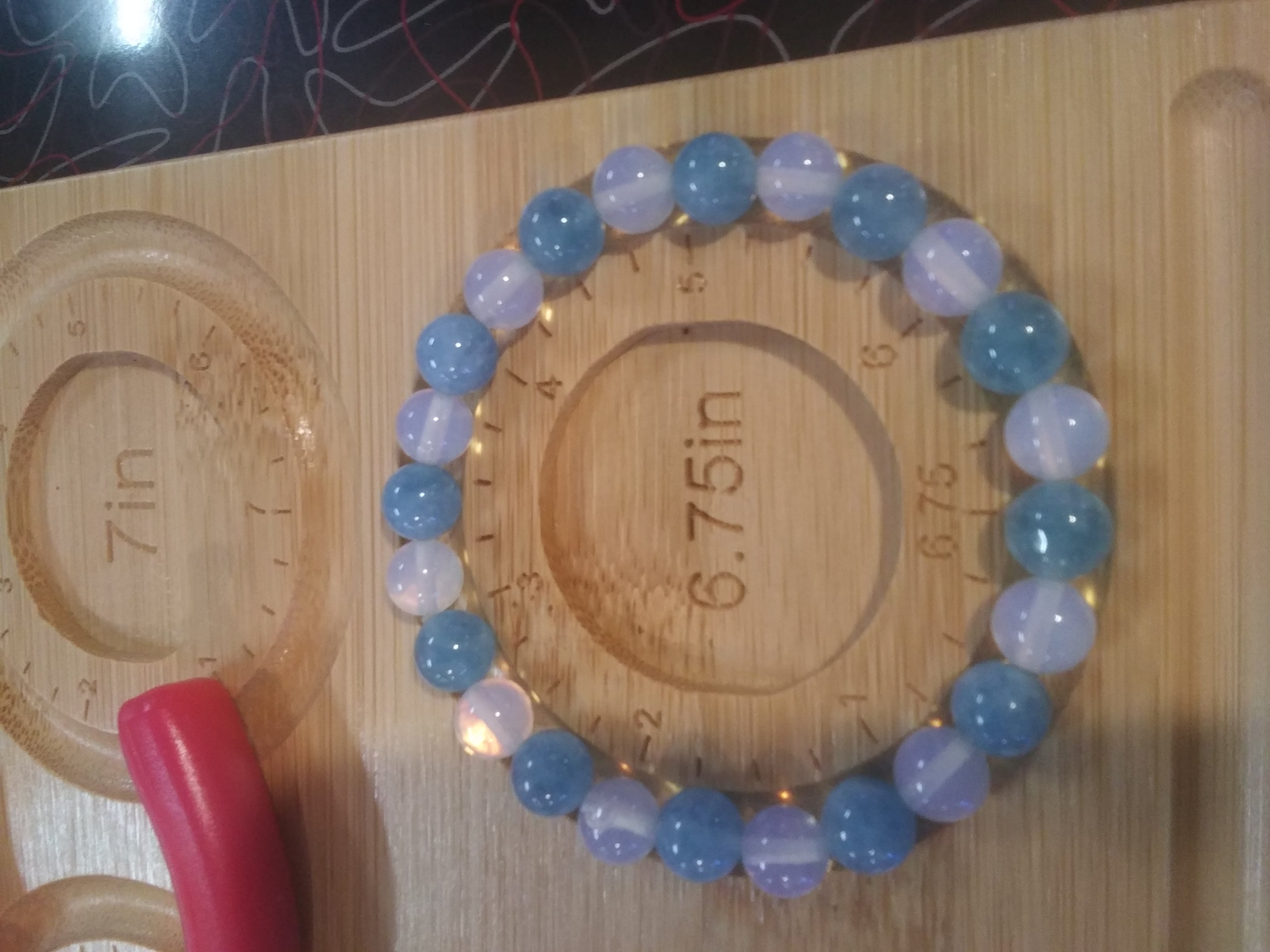 Angelite and moonstone beaded bracelet on a wooden measuring board