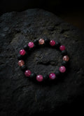 Bracelet with red and black beads on a rock surface