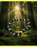 Bracelet of black lava and white howlite stones in a forest with trees in the background