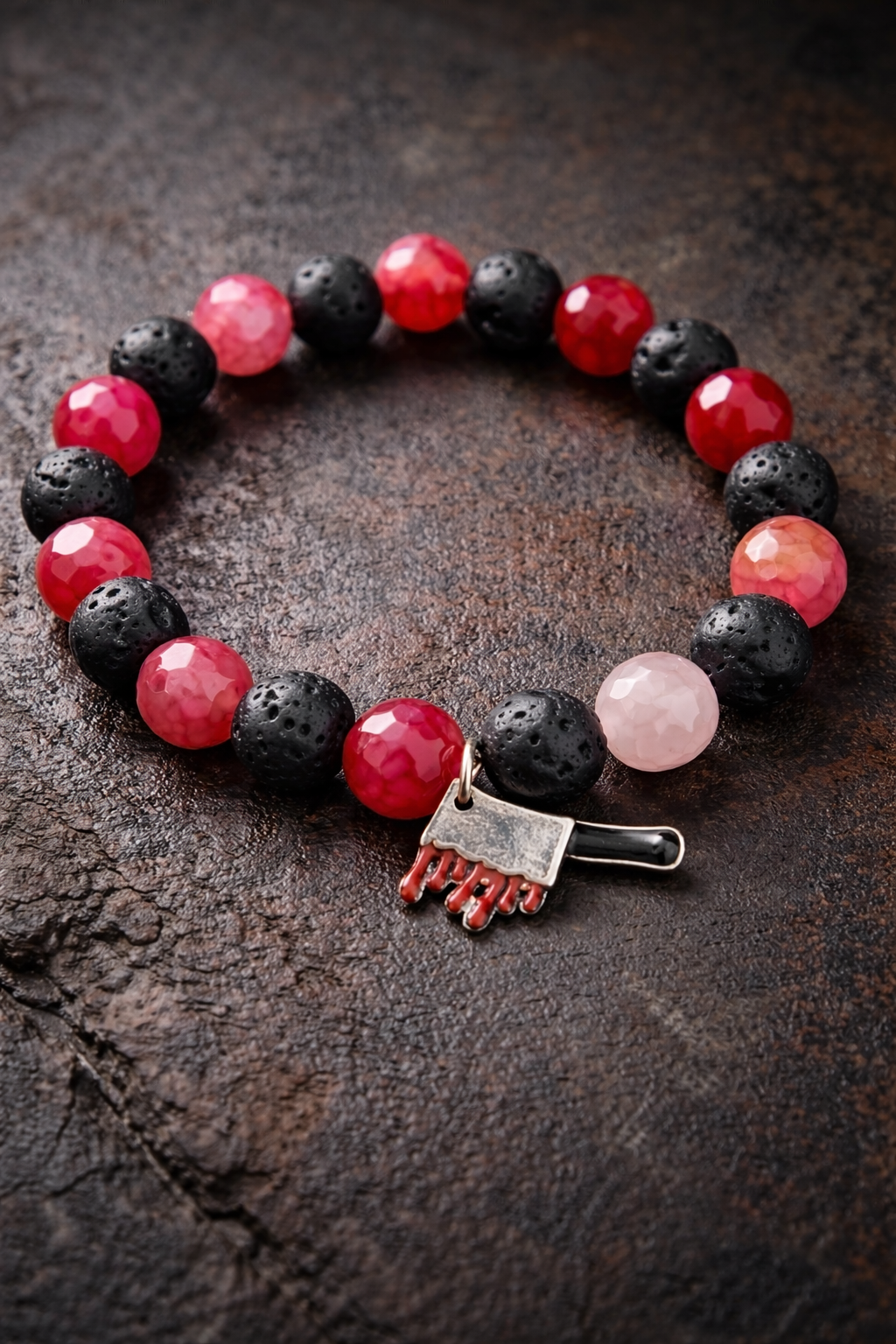 Bracelet with black, red, and pink beads on a dark surface