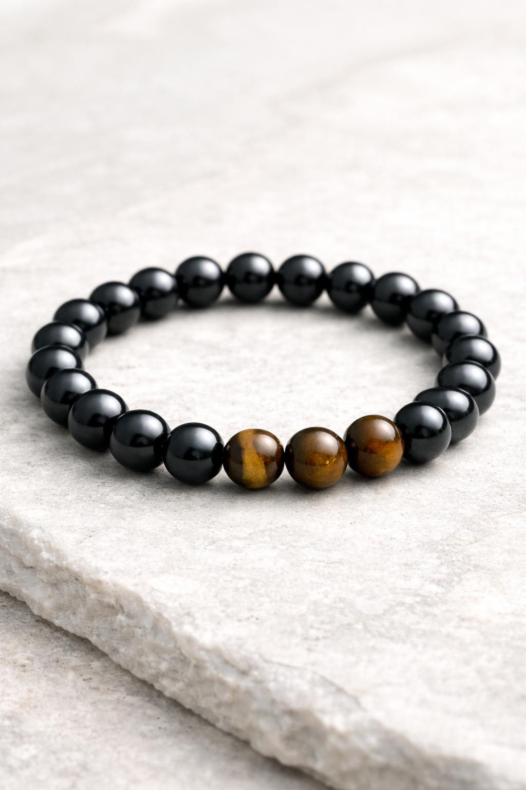 Black beaded bracelet with a brown tiger eye stone on a light gray surface