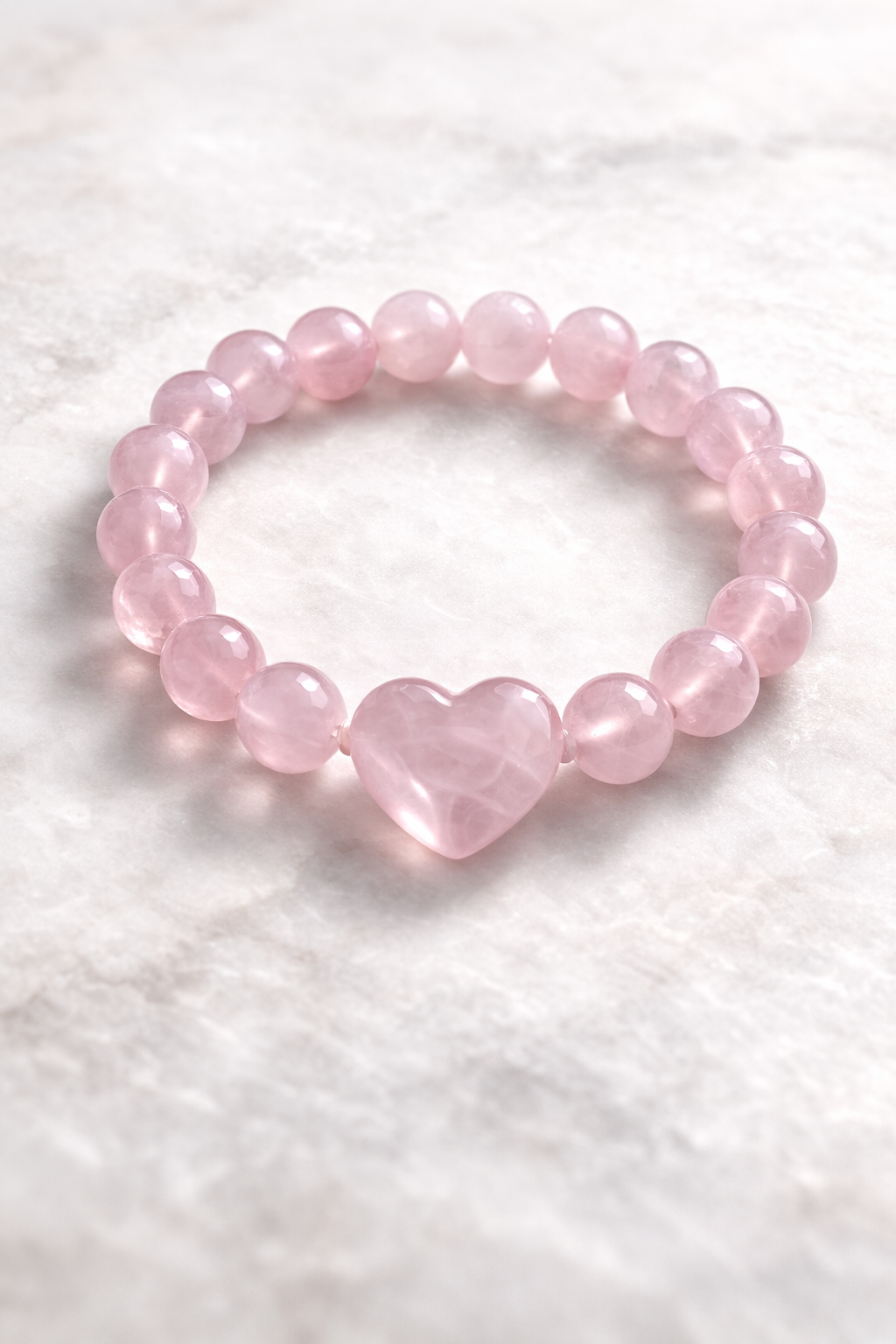 Pink heart-shaped bead bracelet on a white textured background