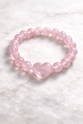 Pink heart-shaped bead bracelet on a white textured background