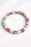 Multicolored beaded bracelet with gold accents on a white background