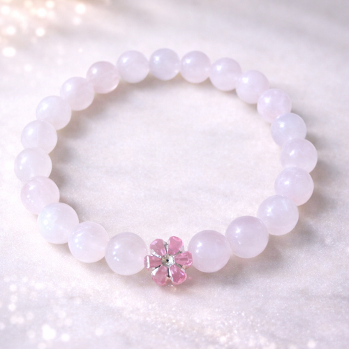 Pink beaded bracelet with a pink flower charm on a white background