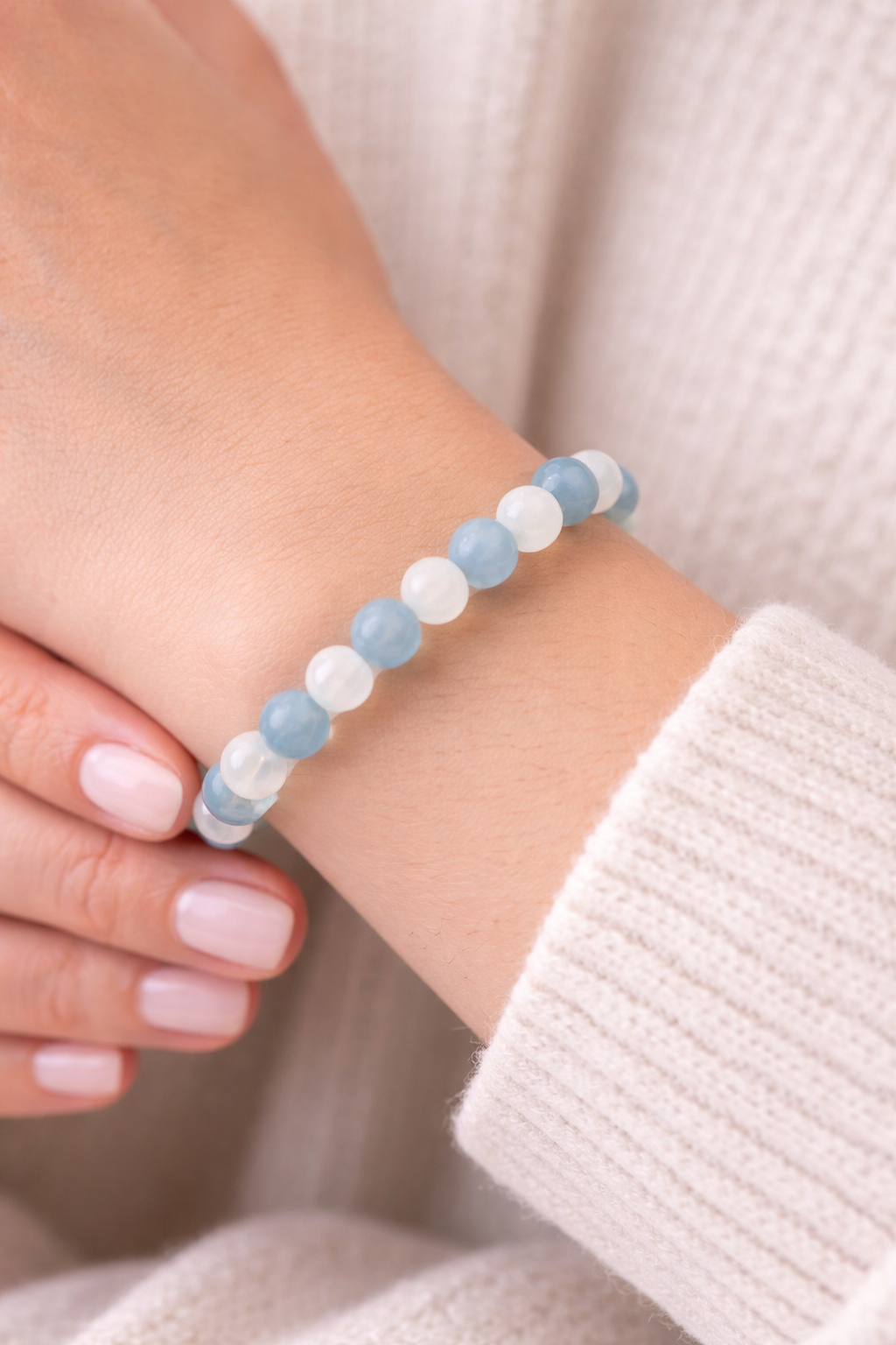 Close-up of a wrist wearing a blue and white beaded bracelet against a neutral background.