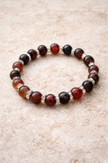 Bracelet with brown and black beads on a beige surface
