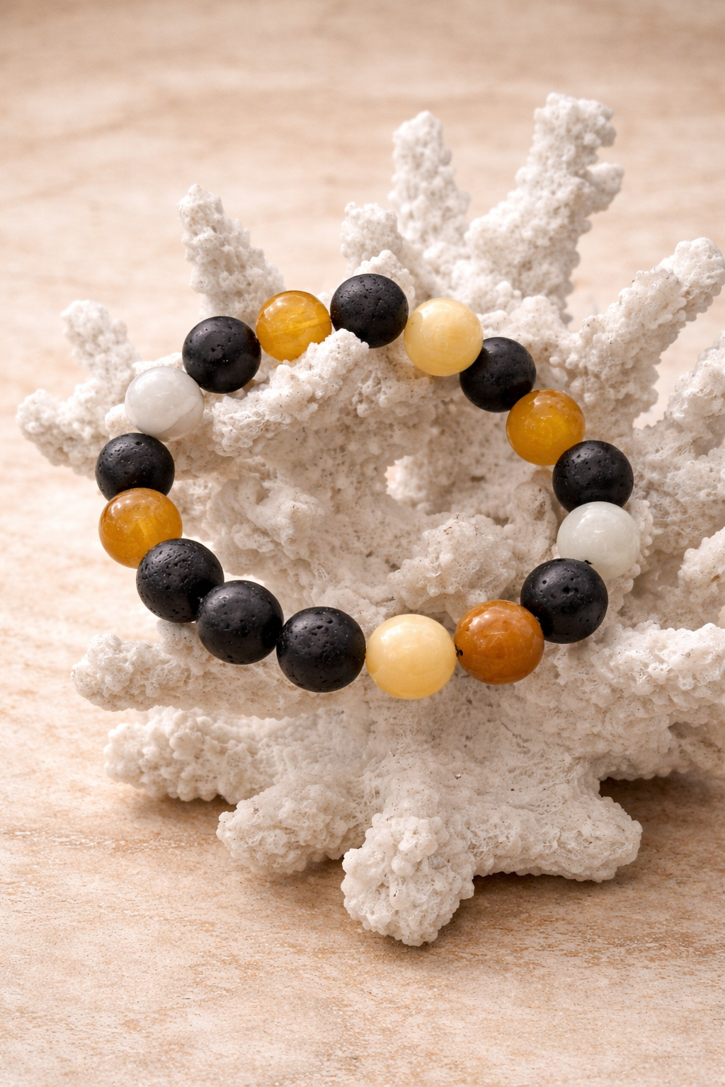 Beaded bracelet with black, orange, and white beads on a piece of white coral.