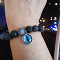 Bracelet with blue eye charm on a wrist against a blurred city lights background