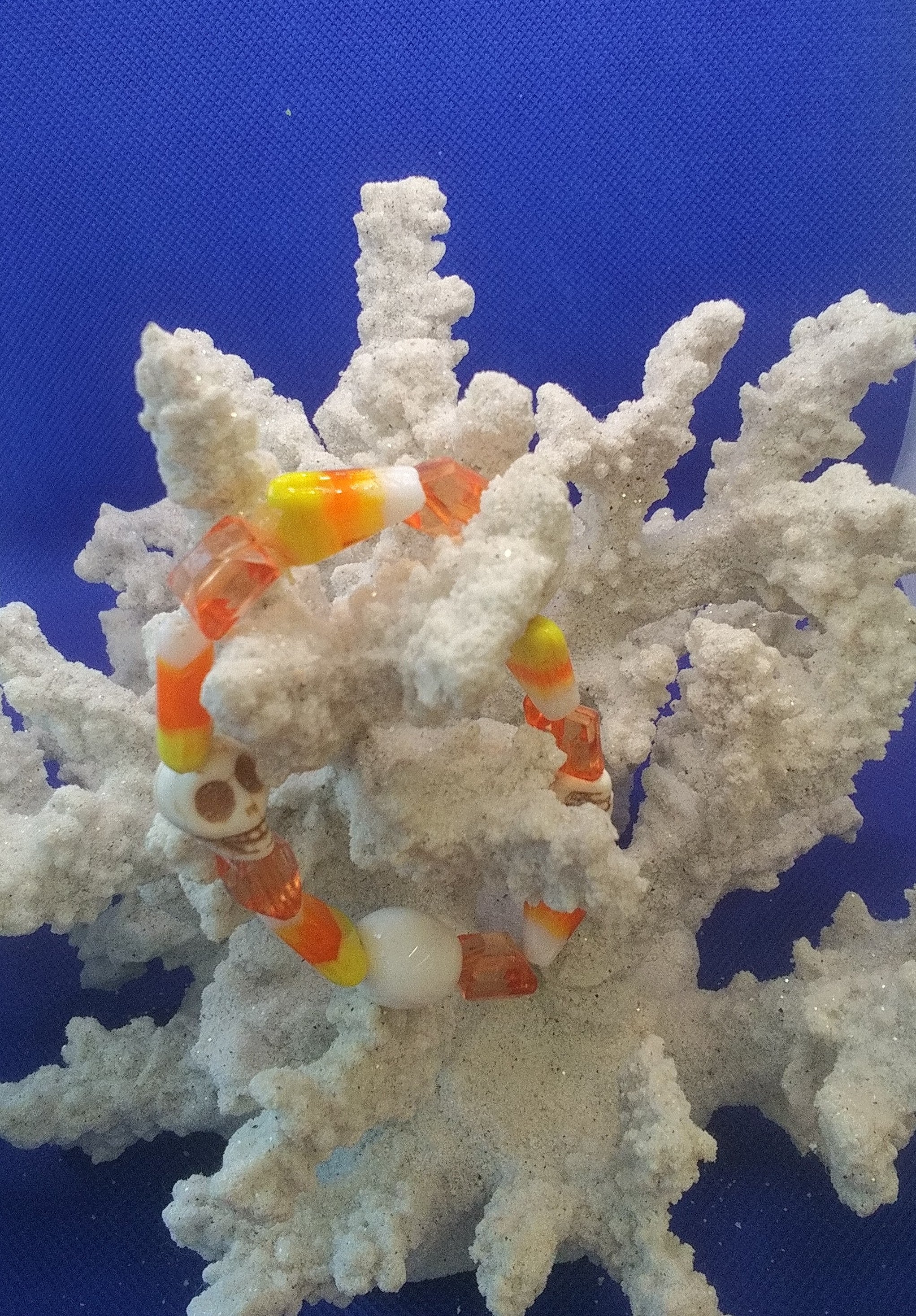 A festive stretch bracelet featuring candy corn-colored beads and playful skull accents, perfect for adding a spooky yet fun touch to any Halloween outfit.
