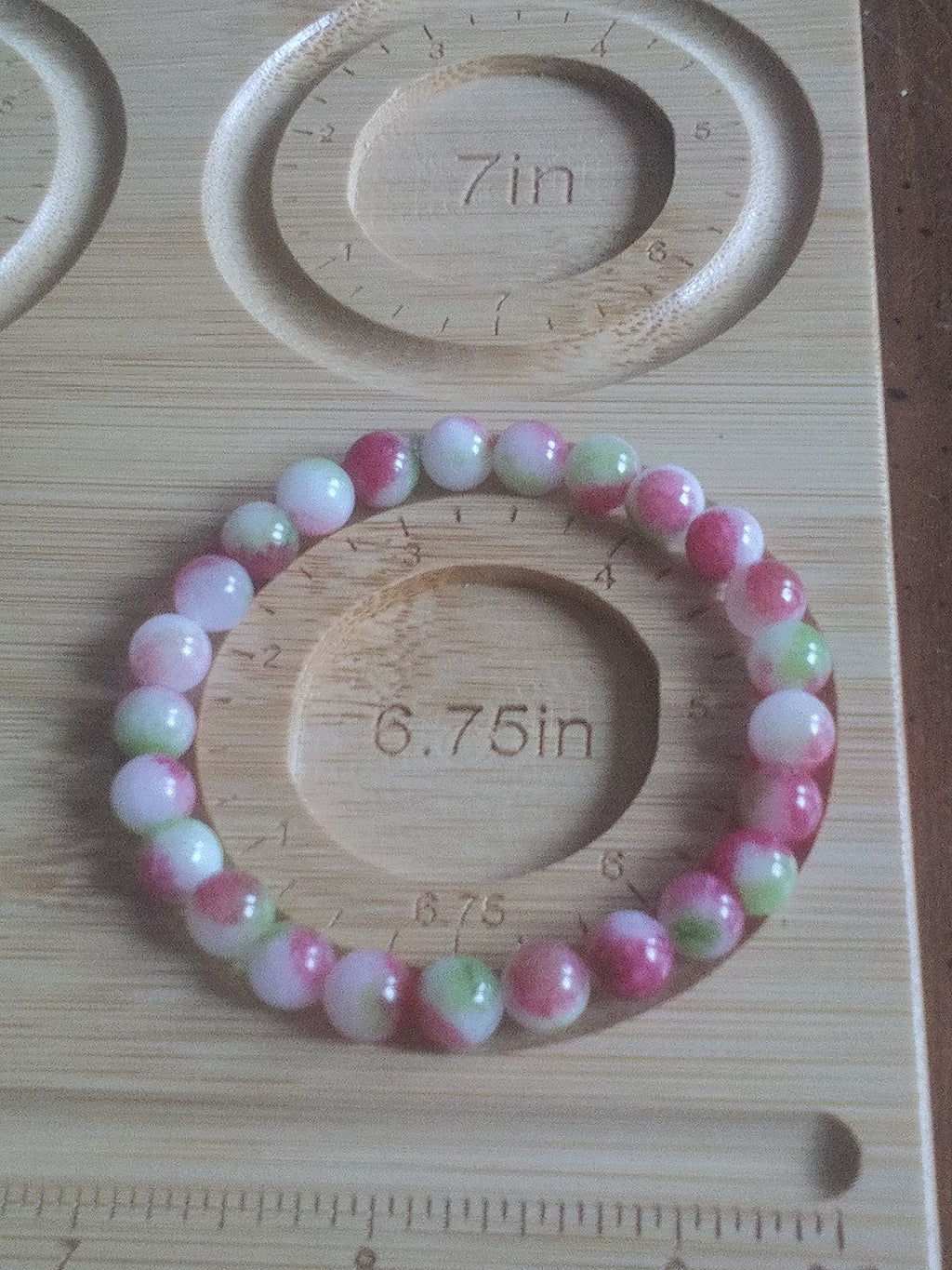 Beaded bracelet on a wooden board with measurements, on a wooden surface.