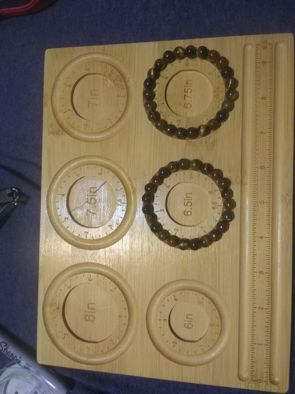 Tiger eye bracelets on a wooden measuring board with circular measurements  on a blue surface