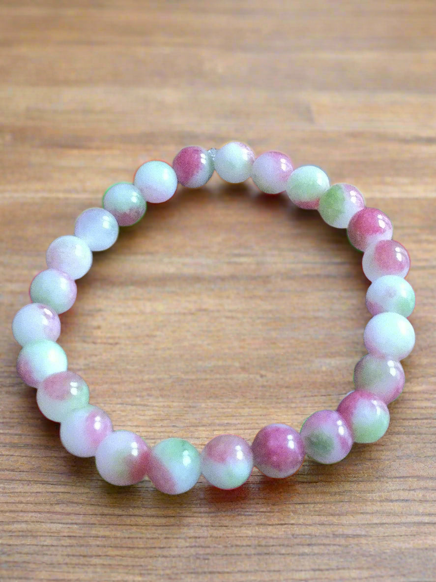 Beaded bracelet with pink and green beads on a wooden surface